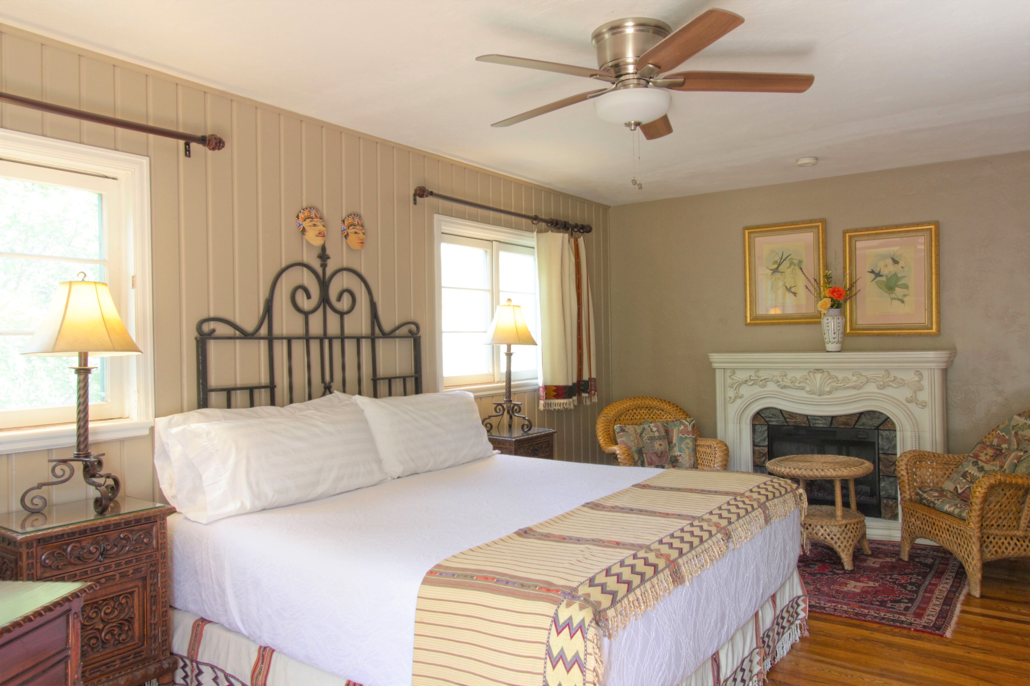 At one of the best hotels in Farmington NM, you'll find a guest room complete with a fireplace, seating area, and a large bed framed by windowns, nightstands, and lamps.