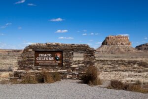 The Chaco Culture National Historical Park sign with ruins in the background